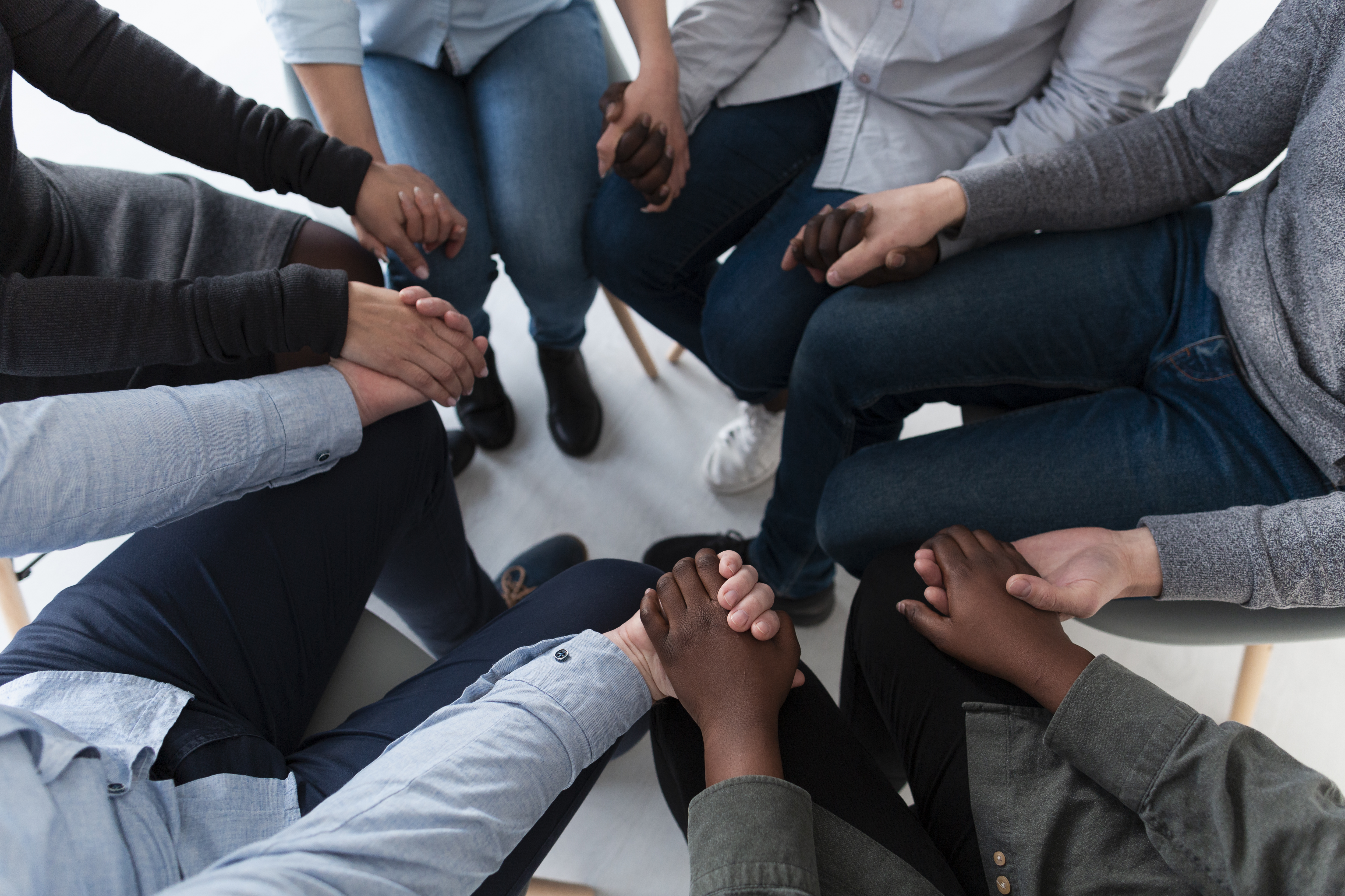 Grupo de pessoas de diversas etnias com as mãos unidas em círculo