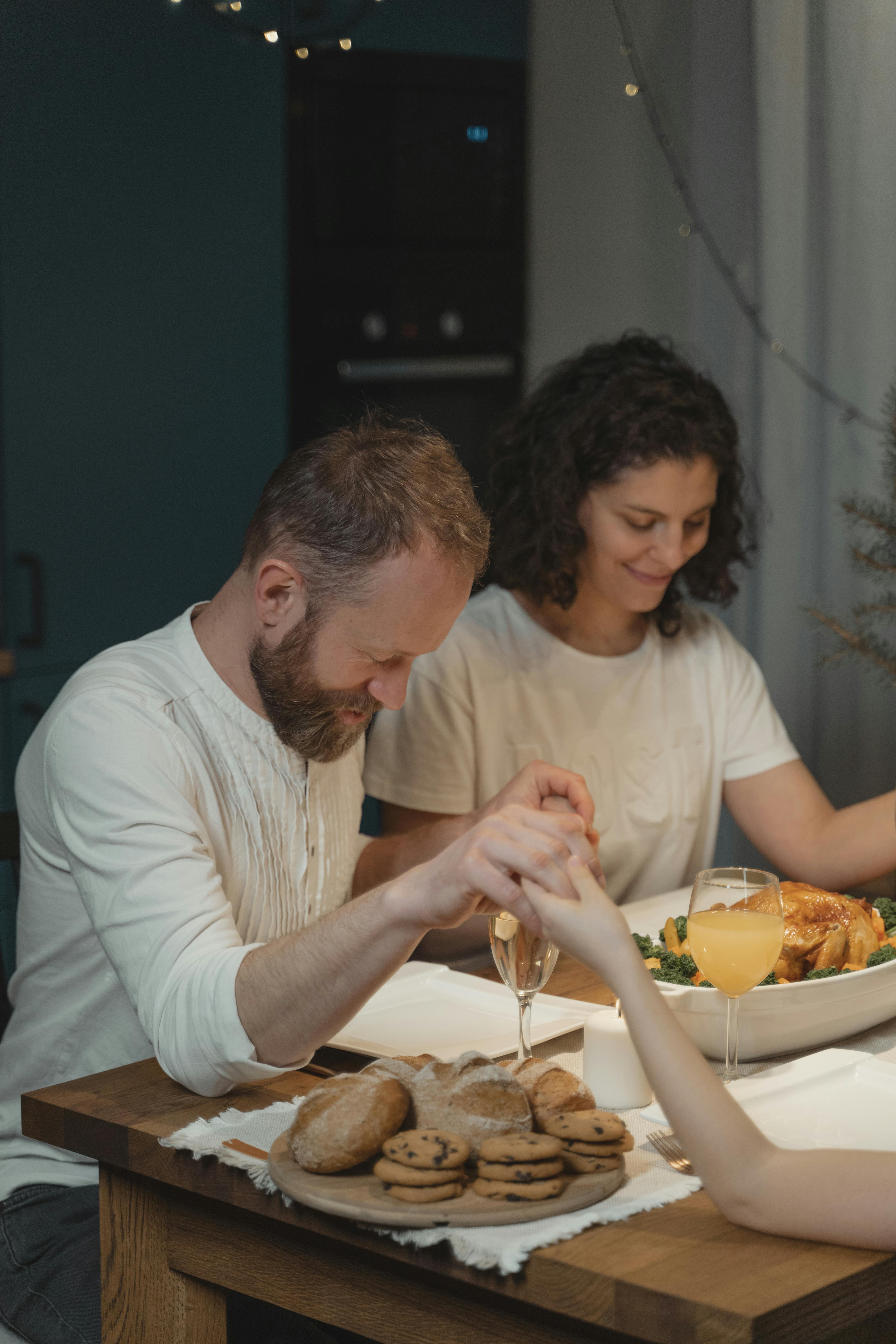 Casal orando de mãos dadas antes de uma refeição.
